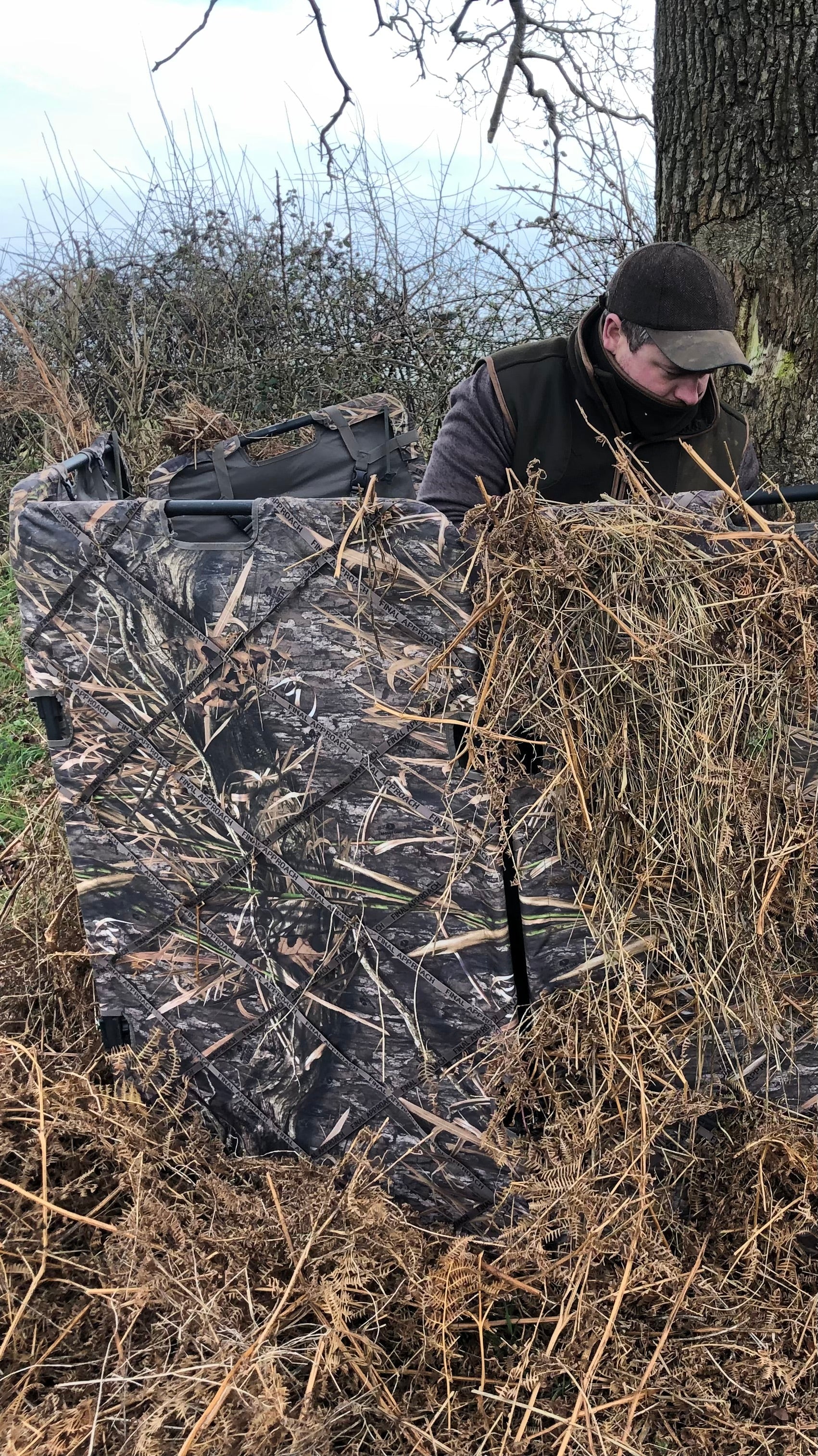 Camouflage blind with pigeon shooter in the field showing hide